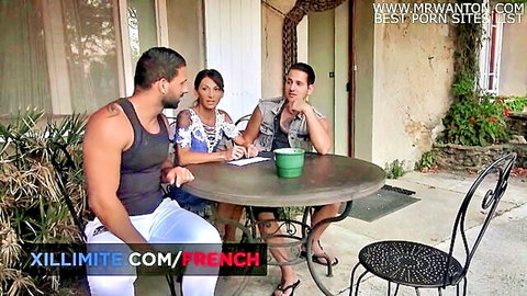 French brunette babe in sheer top chats with two muscular studs at outdoor table