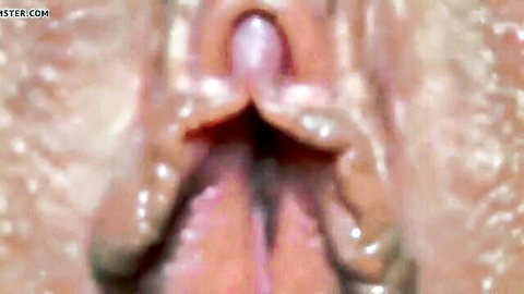 Extreme close-up of wet aroused vulva with prominent clitoris and milky squirt