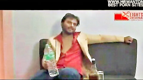 Relaxed Indian man in open suit jacket holding drink in hotel romance scene