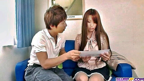 Skinny Japanese girl with long hair in short skirt sits with boyfriend on couch reading letter
