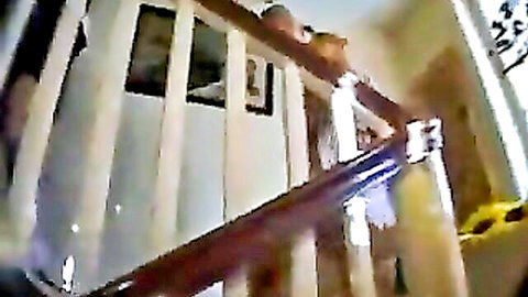 Blurry low-angle shot of wooden staircase railings and glass panels in amateur home video