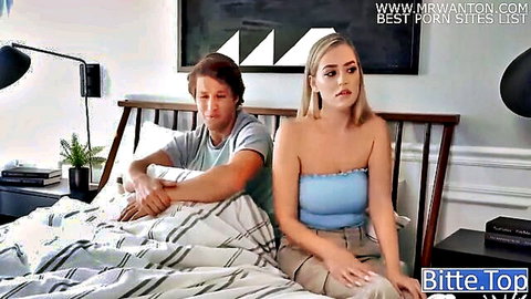 Emotional blonde woman in tube top sits with man on bed, clothed couple scene