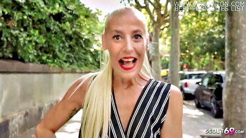 Excited blonde MILF cougar smiling with deep cleavage in striped top on street pick up