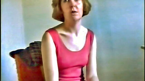 Redhead woman in tight red tank top with open mouth sitting on chair