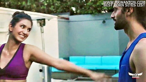 Smiling busty Indian babe in purple sports bra pulls muscular bearded hunk by poolside