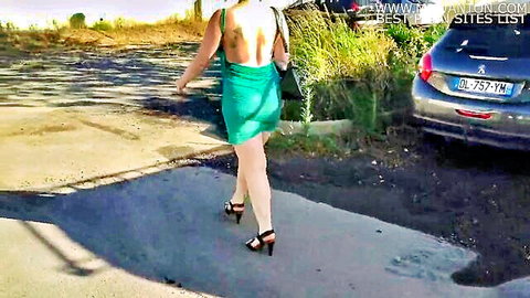 Slim babe in skimpy backless green mini dress walking in public parking lot high heels