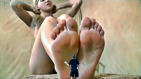 Blonde giantess spreads huge bare feet around tiny clothed man, nude pussy and soles dominating him