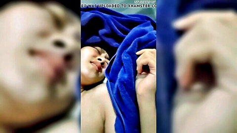 Blurry close-up of nude Thai girl lying with blue towel, mouth open during intimate scene