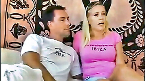 Blonde woman and man in matching Ibiza t-shirts sitting close on bed
