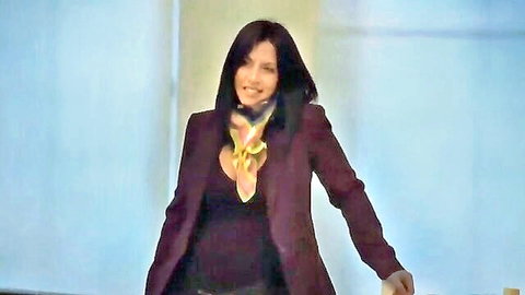 Smiling brunette woman in maroon blazer with cleavage, colorful scarf