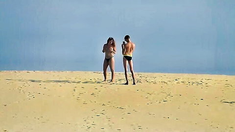 Topless woman in thong flashes on sandy dunes as man takes photo