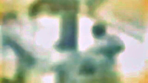 Blurry yellow-tinted photo of an equestrian statue with rider on horse pedestal outdoors
