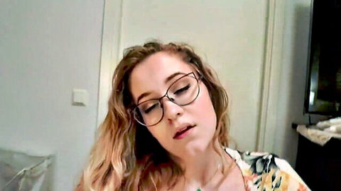 POV closeup of sexy young woman with glasses and wavy hair pouting lips in floral top