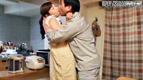 Asian wife passionately kissing male friend at home in kitchen