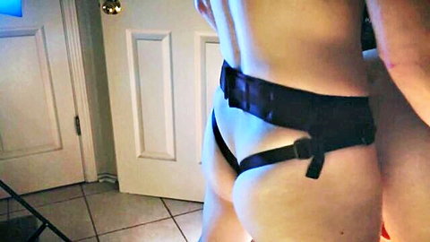 Nude man in black harness bent over for pegging doggy style