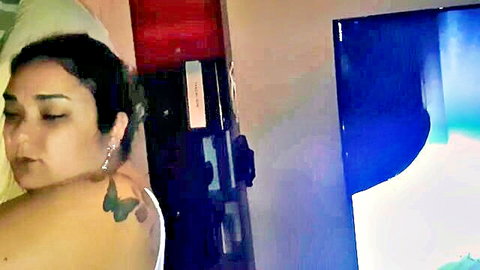 Latina with butterfly tattoo lies topless on bed showing side boob in amateur homemade bedroom