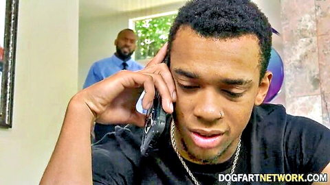 Young black guy on intense flip phone call with suited black man watching behind Dogfart Network