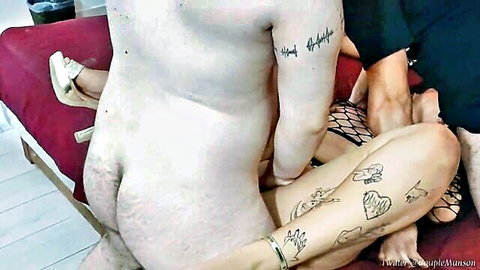 Naked man with big pale ass and balls between tattooed woman's spread fishnet legs during sex