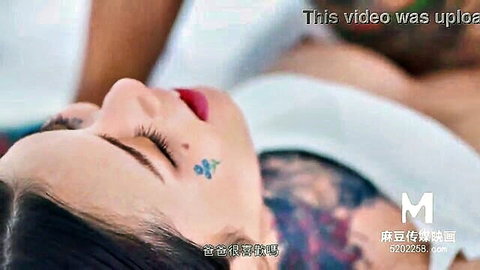 Ai Qiu lying nude on bed, Asian beauty with face tattoo and serene expression