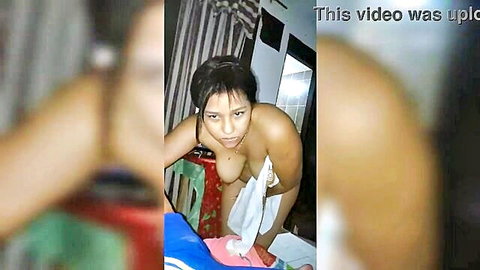 Petite Asian brunette teen squats topless holding white towel over pussy teasing viewer