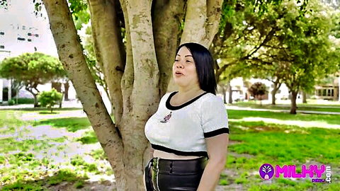 Curvy Latina MILF with huge natural tits teasing in tight white crop top and leather pants outdoors in park
