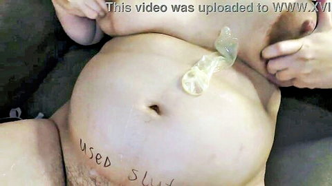 Pregnant belly marked 'Used Slut' with cum-filled used condom in navel