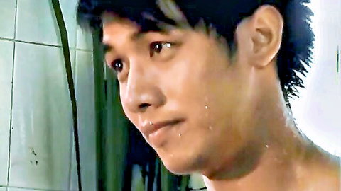 Closeup of young sweaty Asian guy's intense face in tiled shower bathroom
