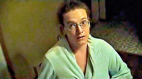 Trans woman in green robe with short hair and glasses, surprised expression
