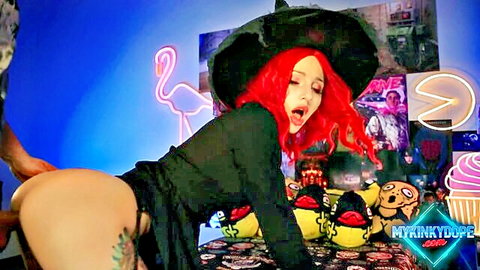 Redhead witch in black dress bent over, man grabbing her ass in Halloween punishment scene