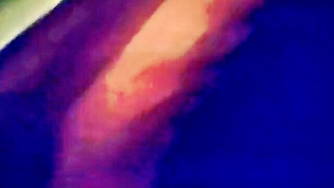 Blurry close-up of mature East Asian man's bare skin in colorful lighting tease