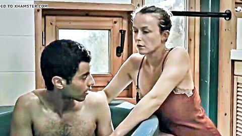 Chloe Andre in red lingerie leaning over shirtless man in bathtub handjob scene