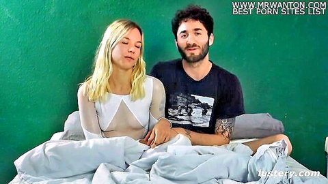 Kitti and Uri cuddling intimately on bed in sheer lingerie and t-shirt