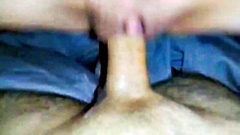 Closeup of thick erect cock head pressed between wet pussy lips on blue sheets