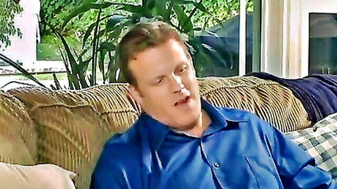 Submissive white man in blue shirt on couch, ready to obey