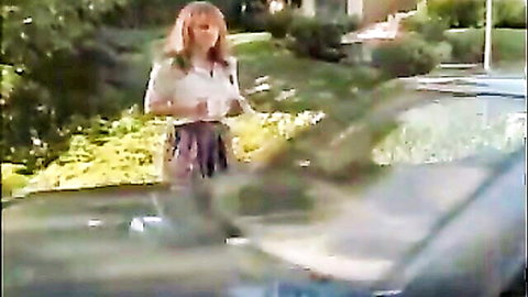 Blonde woman in white blouse and pleated skirt by car in 1993 adult movie