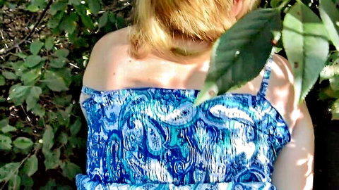 Blonde woman in strapless blue paisley top posing outdoors in forest