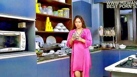 Sexy Indian wife in revealing pink satin robe showing cleavage on phone in kitchen