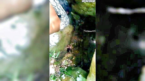 Blurry outdoor scene of Sri Lankan couple near mossy rocks and water stream