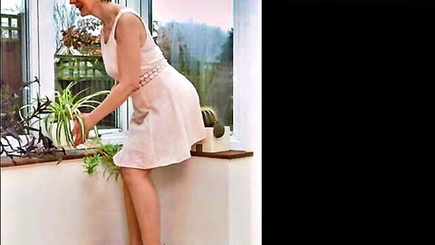 Miss Jones in pink dress bending over plants, teasing upskirt view