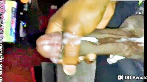 Close-up of large black cock stroked by dark hand with cum dripping
