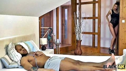 Seductive white woman in black lingerie watches muscular black man in bed