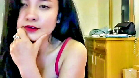 Seductive Asian babe in pink camisole posing with hand on chin and red lips