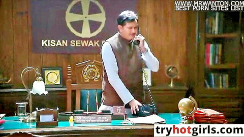 Indian man in vest talking on phone at Kisan Sewak office desk with porn watermarks