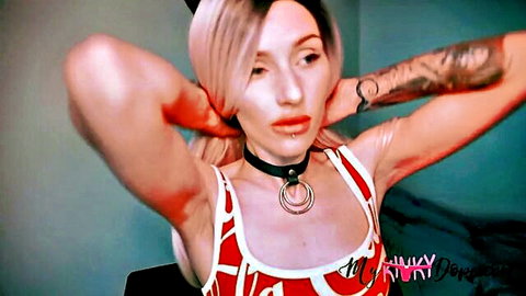 Blonde tattooed woman in choker and red dress posing kinkily for solo masturbation