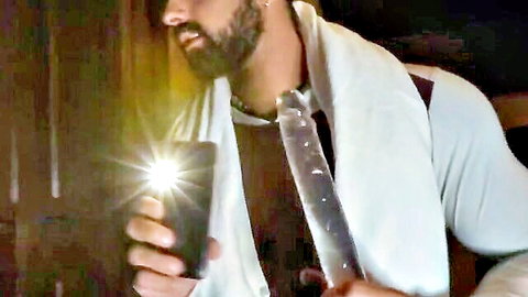 Muscular bearded man in white towel holding phone flashlight, teasing porn scene