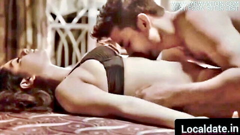 Shirtless muscular Indian man kissing and groping busty woman's exposed tits passionately on bed
