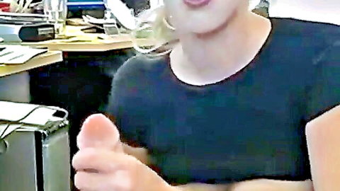Blonde babe smiles happily giving thumbs up in office wearing tight black top