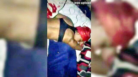 Muscular ebony woman in black sports bra and red headscarf from behind on bed