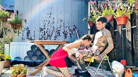 Skinny brunette babe in red skirt fishnets kneels outdoors sucking tattooed guy's hard cock
