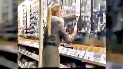 Blonde babe in fur coat reaches for faucet in crowded hardware store aisle